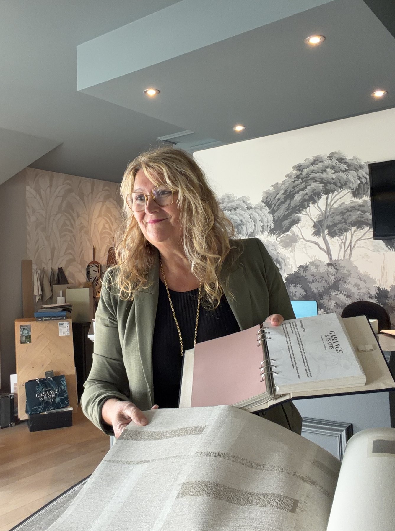 Myriam Blin feuillette des échantillons de tissus et papiers peints pour un projet de décoration