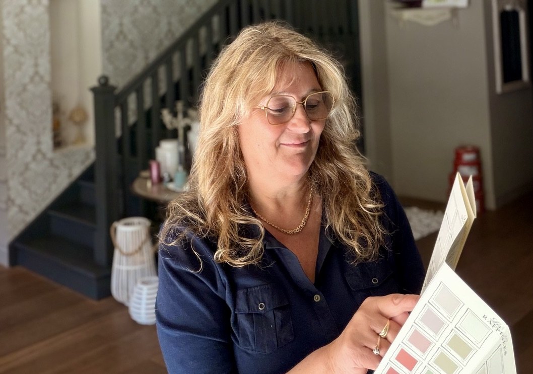 Myriam Blin observe un intérieur, un nuancier à la main
